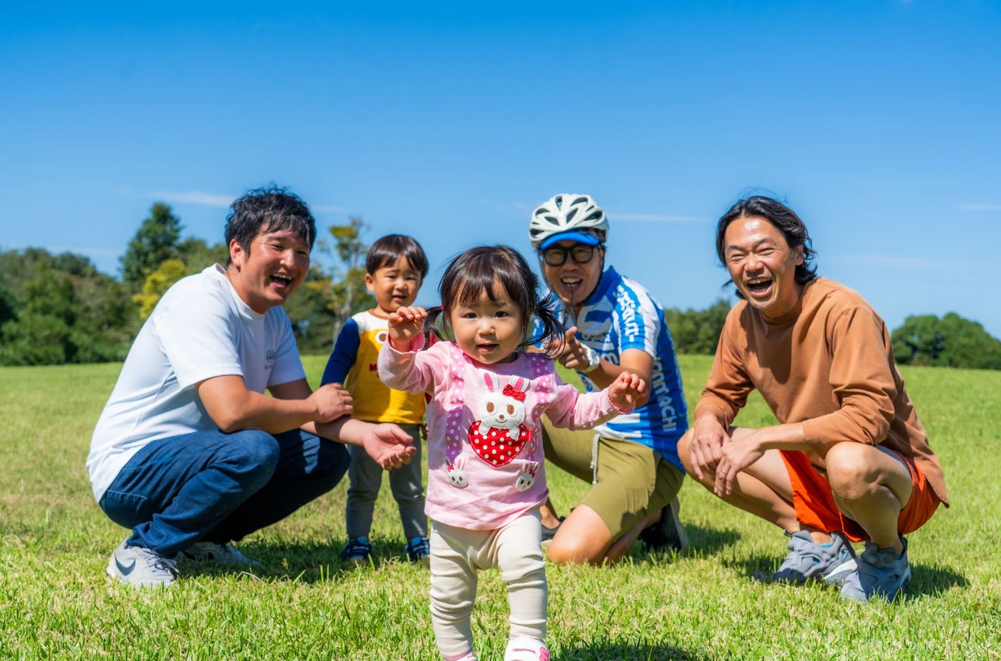 芝生の広場で笑う紀の川アウトドアラインのメンバーと子どもたち